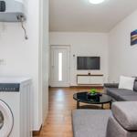 Wohnzimmer mit Sofa, TV und Waschmaschine im Hintergrund.