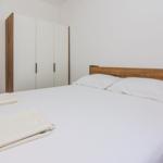 Schlafzimmer mit Doppelbett, Kleiderschrank und Tür.