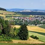 Panorama über eine ländliche Gegend mit Feldern, Wäldern und einem Dorf.