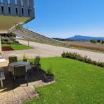 Terrasse mit Tisch, Stühlen und Blick auf Felder und Berge.