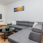 Wohnzimmer mit grauem Sofa, Fernseher und Tisch