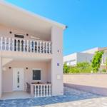 Ein zweistöckiges Haus mit Balkon, Terrasse und Außentreppe.
