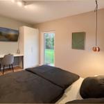 Schlafzimmer mit Bett, Schreibtisch, Kleiderschrank und Zugang zum Garten.