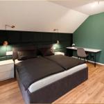 Schlafzimmer mit Doppelbett, Schreibtisch und Fernseher an der Wand.