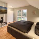 Schlafzimmer mit Bett, TV und Fenster zur Gartenansicht