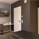 Schlafzimmer mit Bett, Schreibtisch und Wandbild. Tür und Kleiderschrank sichtbar.