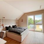 Schlafzimmer mit Doppelbett, Schreibtisch und großem Fenster zur Außensicht.