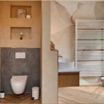 Bad mit Toilette, Waschbecken und Heizkörper. Holzdielenboden und Wandverkleidung.