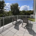 Terrasse mit zwei Liegestühlen und Blick auf grüne Bäume.