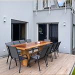 Terrasse mit Holztisch und acht Stühlen vor modernem Haus