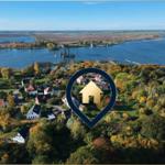Aerial view of a village near a large water body with autumn trees.