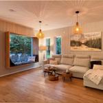 Wohnzimmer mit Sofa, Sitzbank und Holzboden. Fenster mit Blick auf Garten.