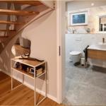 Treppenhaus mit Bücherregal und angrenzender Badewanne mit Waschbecken.