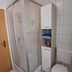 Bad mit Duschkabine, Toilette und Hochschrank.