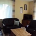 Wohnzimmer mit Ledersofa, Holztisch und Fernseher.