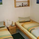 Zwei Einzelbetten mit Streifenbezug, Nachttisch und Wandregal mit Dekor.