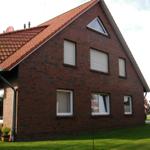 Rotes Ziegelhaus mit Dachgaube und Gartenterrasse.