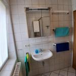 Badezimmer mit Waschbecken, Spiegel und Handtüchern an Halterungen.