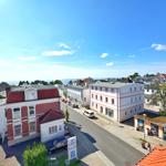 Städtischer Blick mit Straßen, Häusern und Meerblick im Hintergrund.