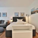 Schlafzimmer mit Bett, Sofa und Wandbildern