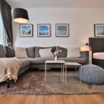 Wohnzimmer mit Sofa, Bett und Wandbildern.