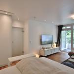 Schlafzimmer mit Bett, Kleiderschrank und TV. Wohnbereich mit Sofa und Balkon.