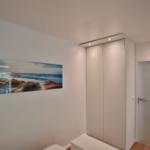 Schlafzimmer mit Kleiderschrank, Tür und Wandbild am Schrank.