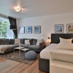 Ein Schlafzimmer mit Sofa, Bett und Fenster zur Terrasse.