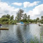 Ein Kajakfahrer auf einem Kanal mit Anlegestellen und Booten.