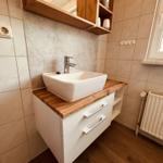 Bad mit Waschbecken, Holzoberfläche und Wandregal.