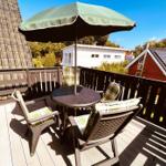 Terrasse mit Tisch, Stühlen und Sonnenschutz. Blick auf Nachbarhäuser und Bäume.