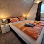 Schlafzimmer mit Doppelbett, Nachttisch und Fenster.