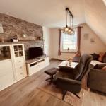 Wohnzimmer mit Sofa, Sessel, TV und Steinwand