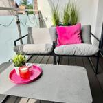 Terrasse mit zwei Sitzgelegenheiten, Tisch und Pflanzen.