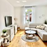 Wohnzimmer mit Sofa, Couchtisch und Fernseher an der Wand.