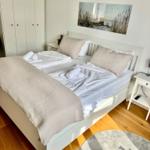 Schlafzimmer mit weißem Bett, Kleiderschrank und Wandbild.