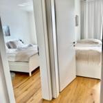 Zwei Schlafzimmer mit weißen Betten und Holzboden sichtbar durch Tür.