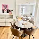 Essbereich mit runder Tisch und vier Stühlen. Wohnbereich mit Sofa und Fenster.