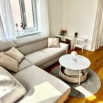 Ein Wohnzimmer mit grauem Sofa, runden Tisch und Holzboden.