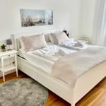 Schlafzimmer mit weißem Bett, Holzboden und Wandbild