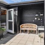 Gedeckter Außenbereich mit Holzbank, Pflanzen und offenen Türen zu Schlafzimmer.