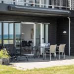 Terrasse mit Tisch, Stühlen und Liegestuhl. Durchgehende Glastüren führen ins Haus.