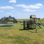 Großer Spielplatz mit Rutsche, Schaukel und Trampolin. Blick auf das Meer.