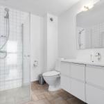 Badezimmer mit Dusche, Toilette und Waschbecken mit Spiegel.