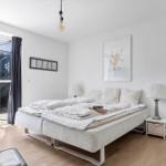 Schlafzimmer mit Doppelbett, Nachttisch und Fenster zur Terrasse.