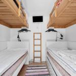 Zwei Etagenbetten mit Matratzen und Nachttischen. Zwischen ihnen steht eine Leiter.