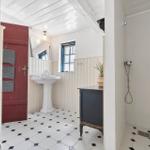 Badezimmer mit Standwaschbecken, Dusche und schwarz-weißem Fliesenboden.