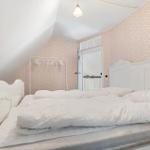 Schlafzimmer mit weißem Bett und gemusterter Wandtapete.