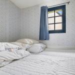 Schlafzimmer mit Bett, Fenster und Wandverkleidung.