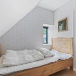 Ein Schlafzimmer mit Holzbett, gemusterter Wand und roter Tür.